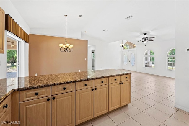 kitchen with light tile patterned floors, plenty of natural light, vaulted ceiling, and ceiling fan with notable chandelier