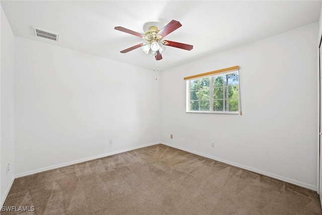 carpeted empty room with a ceiling fan, visible vents, and baseboards