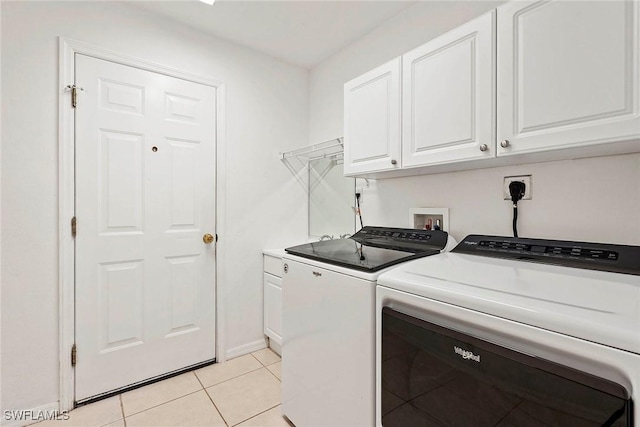 washroom with baseboards, light tile patterned floors, washer and dryer, and cabinet space