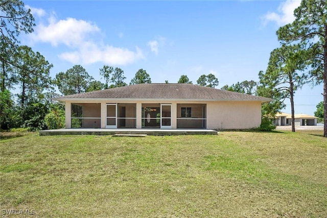 back of house with stucco siding, a lawn, and a sunroom