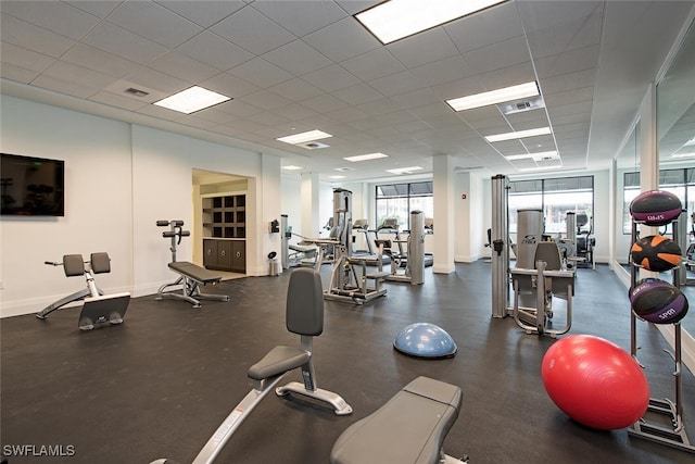 workout area with visible vents, a drop ceiling, and baseboards