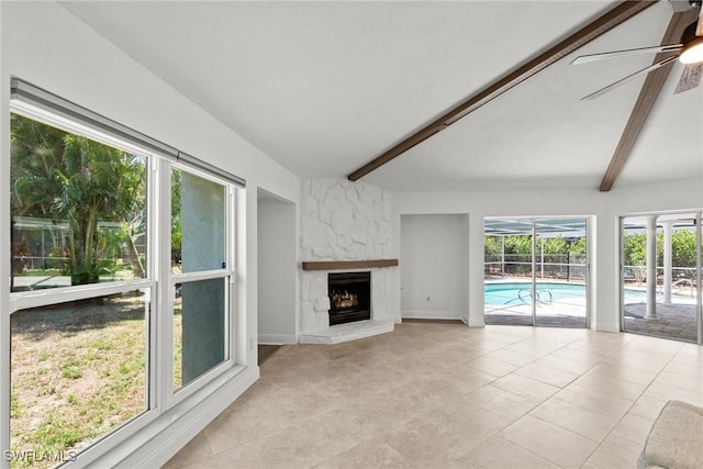unfurnished living room featuring a ceiling fan, light tile patterned floors, beam ceiling, and a fireplace