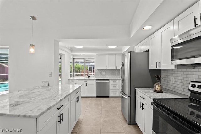 kitchen with decorative backsplash, light stone countertops, white cabinetry, a sink, and appliances with stainless steel finishes
