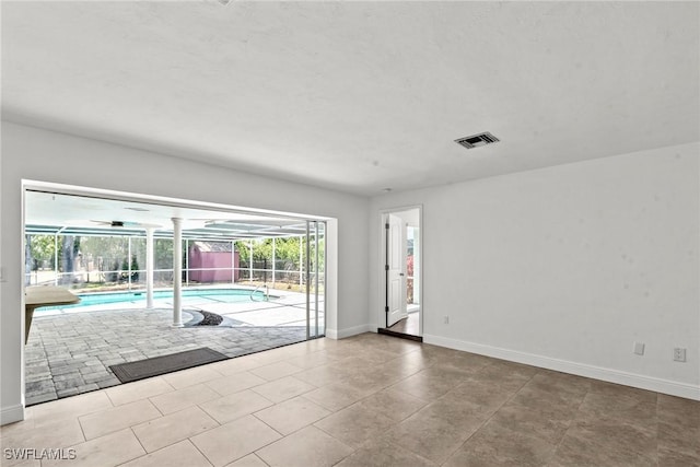 tiled empty room featuring visible vents, baseboards, and a sunroom