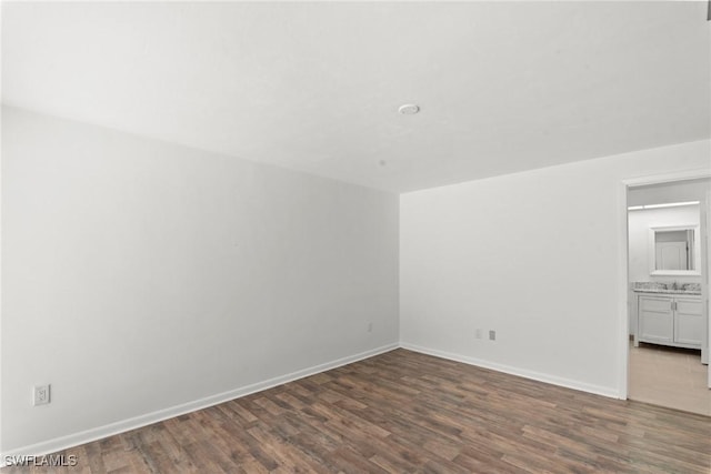 spare room featuring baseboards and dark wood finished floors