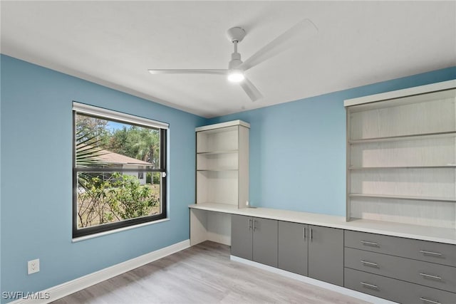 unfurnished office with a ceiling fan, baseboards, and light wood-style floors