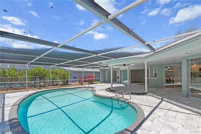 outdoor pool featuring fence, a ceiling fan, glass enclosure, and a patio area