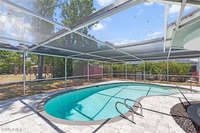 view of swimming pool featuring a fenced backyard, a storage unit, and a lanai