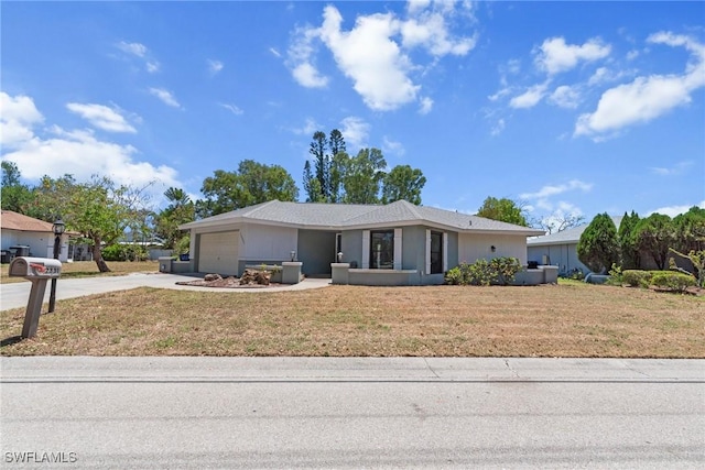 ranch-style house featuring an attached garage, driveway, and a front lawn