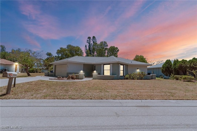 view of front of home with an attached garage, a yard, and driveway