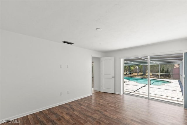 spare room with a sunroom, baseboards, visible vents, and wood finished floors