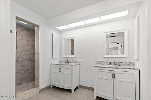 bathroom featuring a sink, baseboards, tiled shower, and two vanities