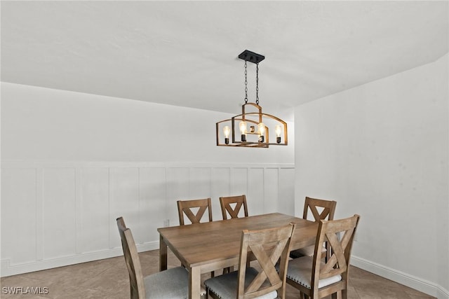 tiled dining space featuring an inviting chandelier and a decorative wall