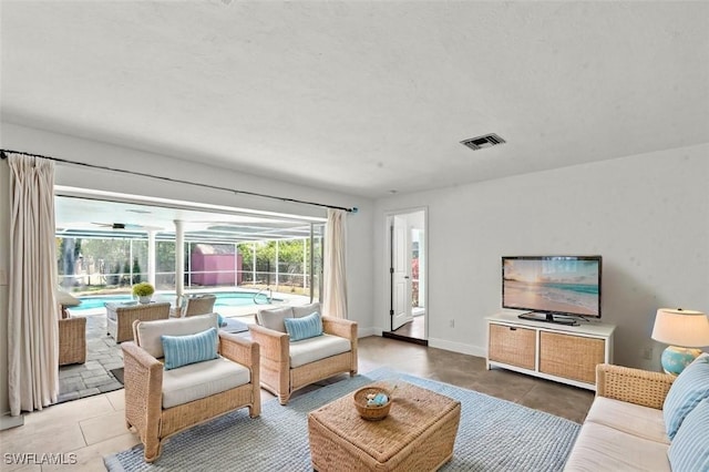 living room featuring light tile patterned floors, baseboards, and visible vents