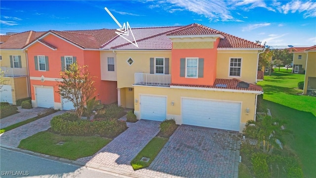 multi unit property featuring stucco siding, decorative driveway, a garage, a tile roof, and a front yard