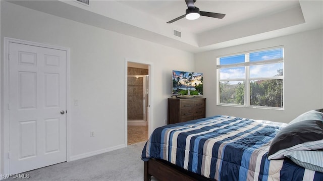 carpeted bedroom with ensuite bath, baseboards, visible vents, a raised ceiling, and a ceiling fan
