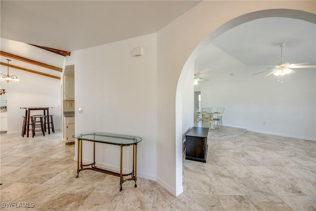 hallway with arched walkways, light stone finish floors, and baseboards