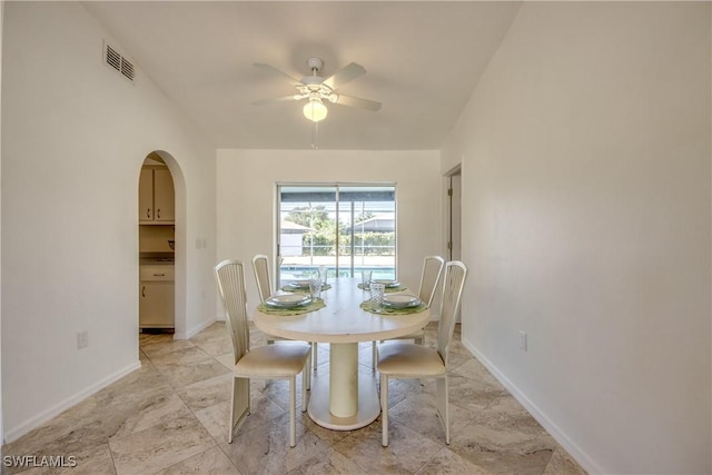 dining area with a ceiling fan, arched walkways, and baseboards