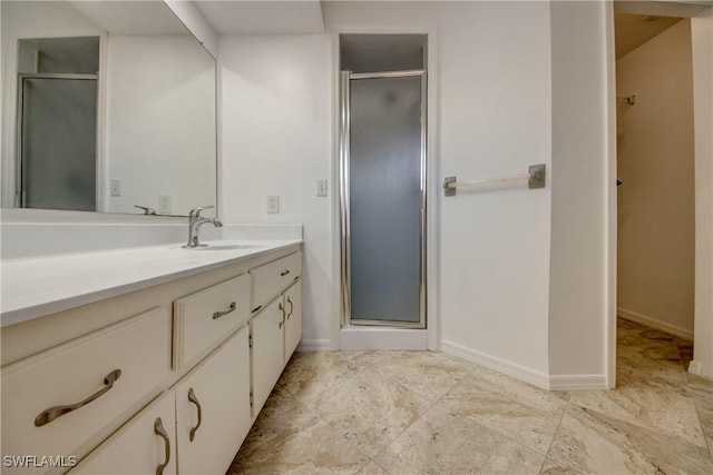 full bathroom with a shower stall, vanity, baseboards, and a spacious closet