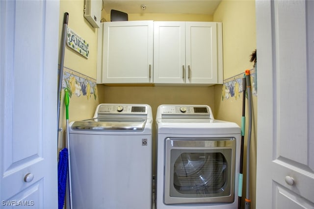 clothes washing area featuring separate washer and dryer and cabinet space