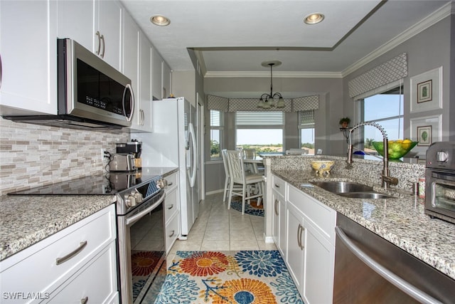 kitchen with a sink, appliances with stainless steel finishes, a notable chandelier, and white cabinets