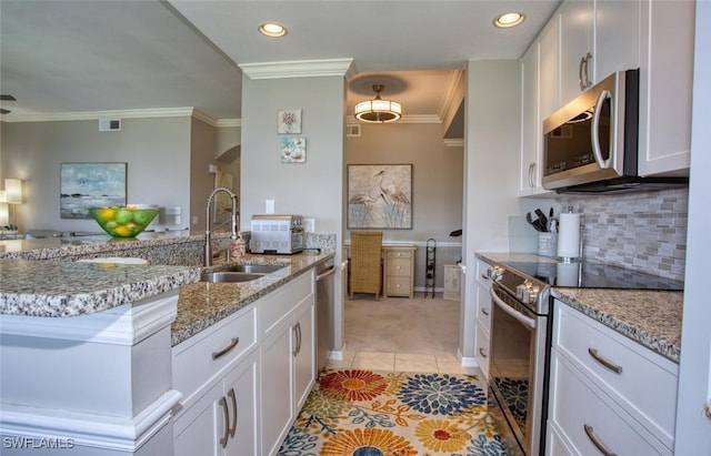 kitchen featuring light tile patterned flooring, light carpet, white cabinetry, a sink, and appliances with stainless steel finishes