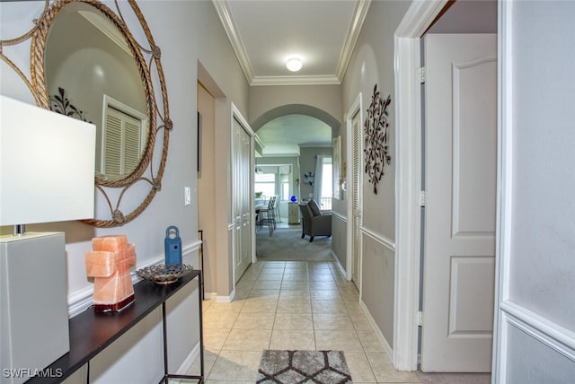 hall featuring crown molding, arched walkways, and light tile patterned flooring