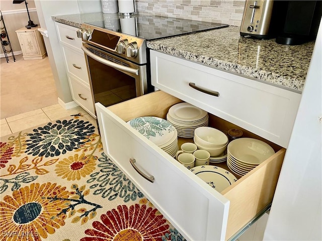 details featuring white cabinets, light stone countertops, decorative backsplash, and stainless steel range with electric stovetop