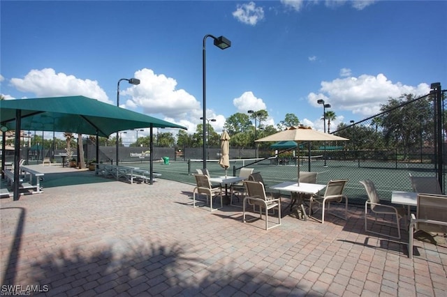 view of property's community with fence and a tennis court