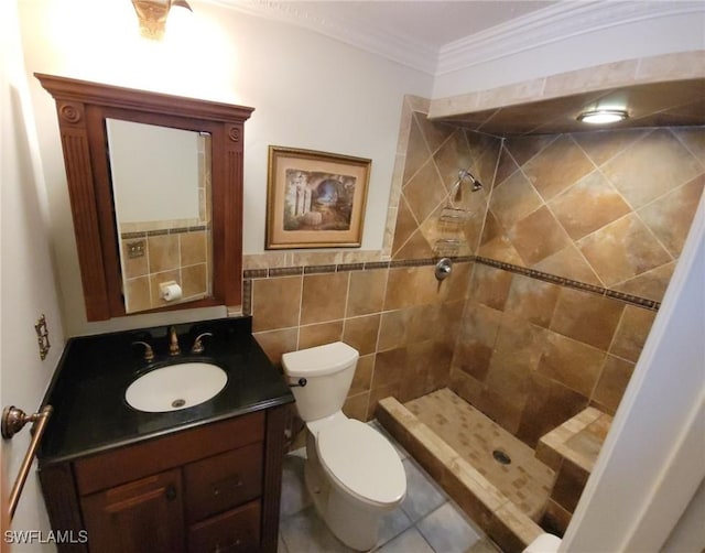 bathroom featuring tiled shower, tile walls, toilet, vanity, and crown molding