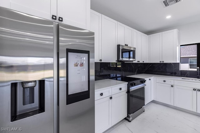 1111 SW Embers Ter, Cape Coral, FL 33991 - kitchen with appliances with stainless steel finishes, light marble finish flooring, white cabinets, decorative backsplash, and recessed lighting