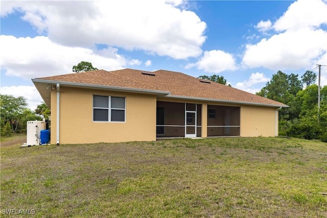 back of property with a lawn, stucco siding, a sunroom, and roof with shingles
