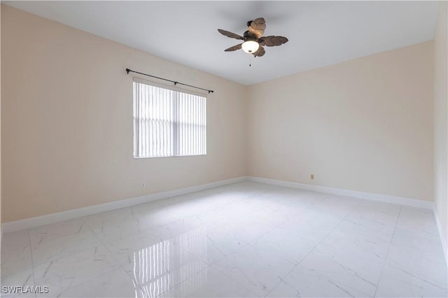 unfurnished room featuring marble finish floor, ceiling fan, and baseboards