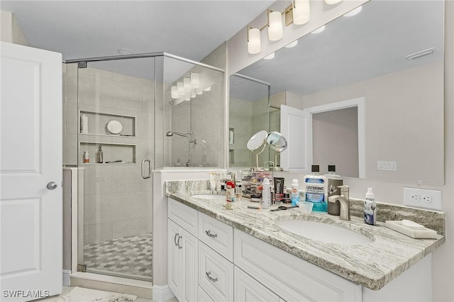 full bath featuring visible vents, a stall shower, double vanity, and a sink