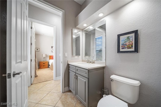 bathroom with toilet, tile patterned flooring, vanity, and ensuite bath