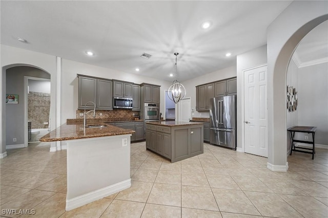 kitchen featuring a sink, stainless steel appliances, a kitchen island, arched walkways, and a peninsula