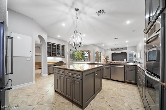kitchen featuring arched walkways, stainless steel appliances, ceiling fan with notable chandelier, gray cabinetry, and visible vents