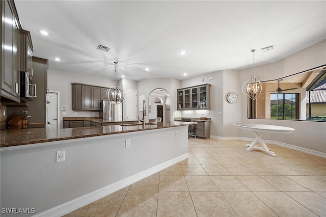 kitchen with an inviting chandelier, dark stone counters, visible vents, and a sink
