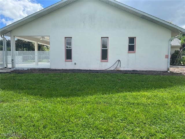 2875 18th Ave SE, Naples, FL 34117 - back of property with a lawn, ceiling fan, fence, and stucco siding