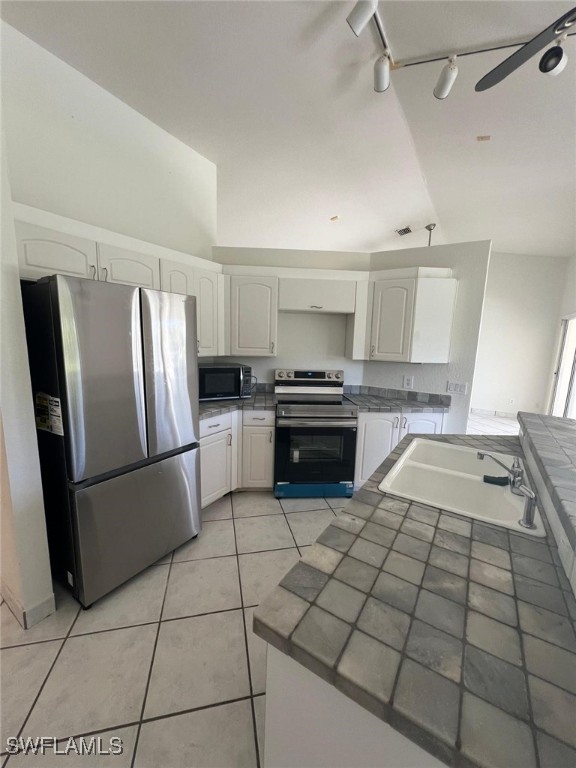 2875 18th Ave SE, Naples, FL 34117 - kitchen with track lighting, appliances with stainless steel finishes, tile countertops, and white cabinetry