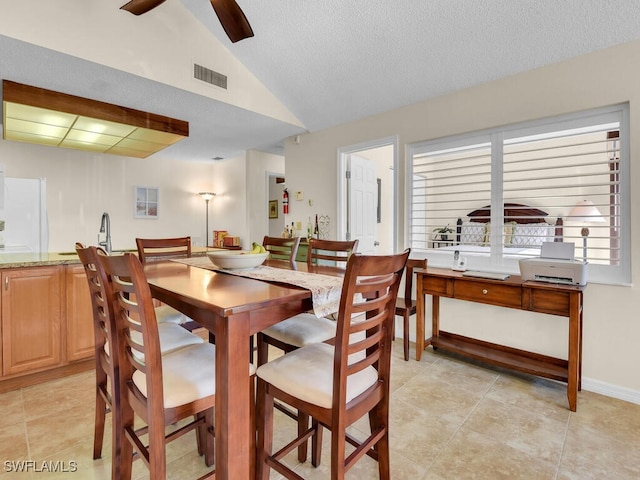 dining room featuring lofted ceiling, a textured ceiling, visible vents, ceiling fan, and light tile patterned flooring