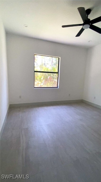 empty room featuring a ceiling fan and baseboards