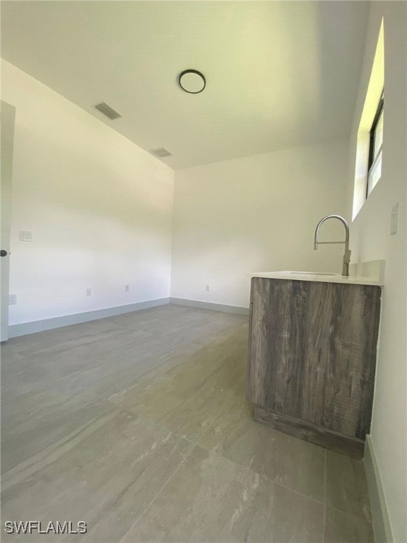 empty room with a sink, visible vents, and baseboards