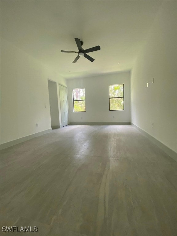 empty room featuring a ceiling fan and baseboards