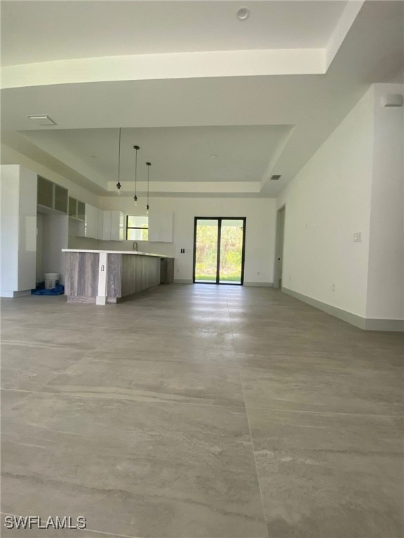 unfurnished living room featuring baseboards and a tray ceiling