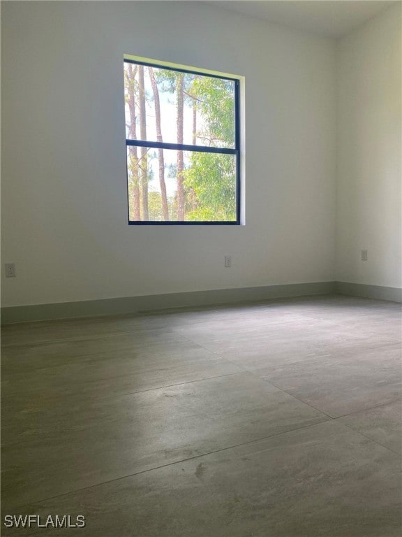 spare room featuring concrete flooring and baseboards