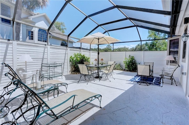 view of patio with a fenced backyard, glass enclosure, and outdoor dining space