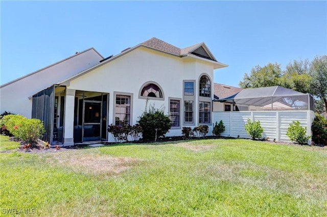 view of front facade featuring a sunroom, a front lawn, and stucco siding