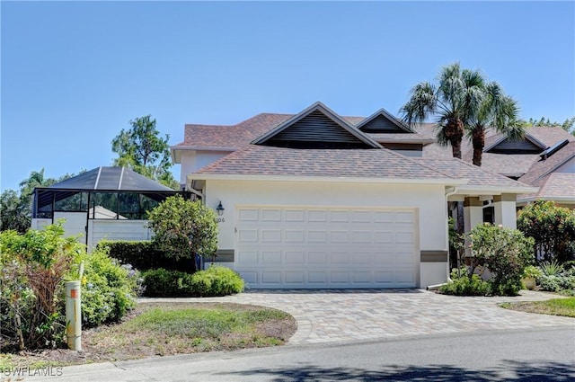 view of front of property with a garage, roof with shingles, stucco siding, and decorative driveway