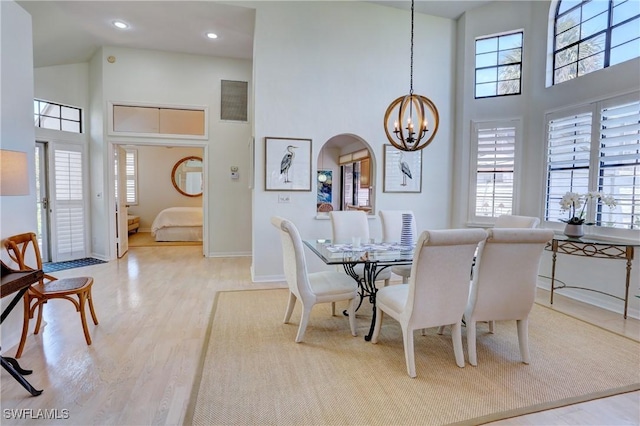 dining space featuring an inviting chandelier, baseboards, wood finished floors, and a towering ceiling